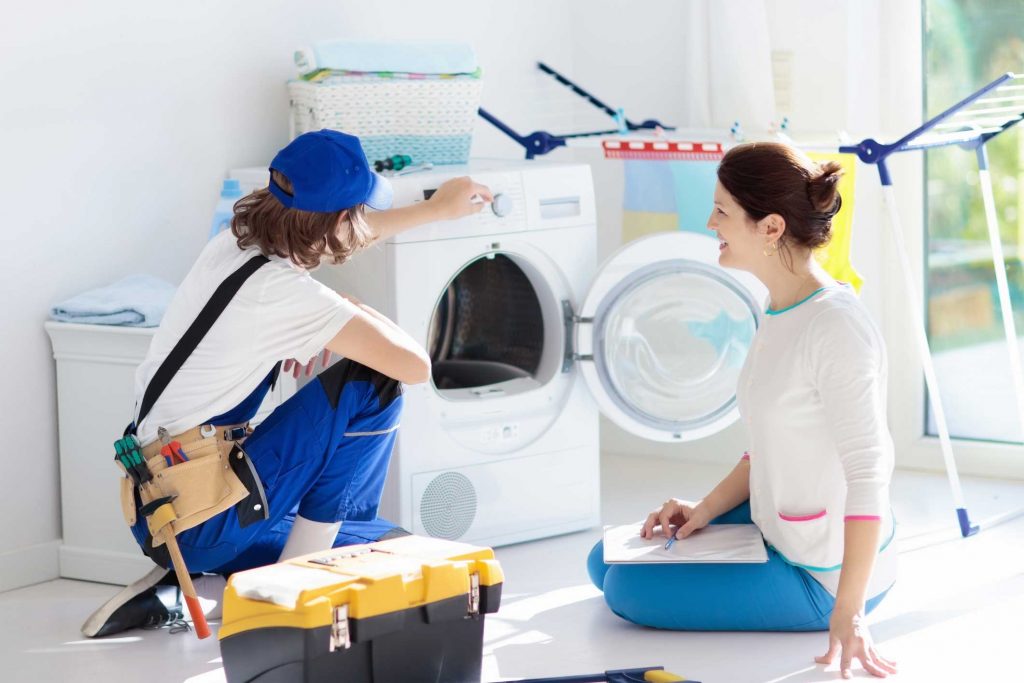 a technician repairing a washer while woman is watching - appliance repair service North Charleston