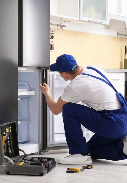 a technician repairing a refrigerator - North Charleston Appliance Repair Pros